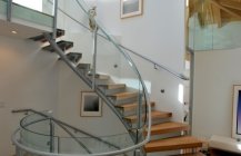 Фото винтовой лестницы со стеклянными перилами.